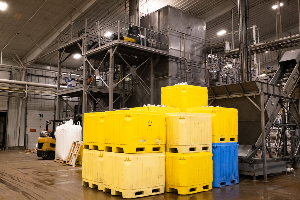 Industrial food byproduct management system with collection containers and recovery equipment inside a food processing facility.